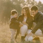 A cheerful family bonding outdoors with a soccer ball, enjoying a sunny day in the grass.